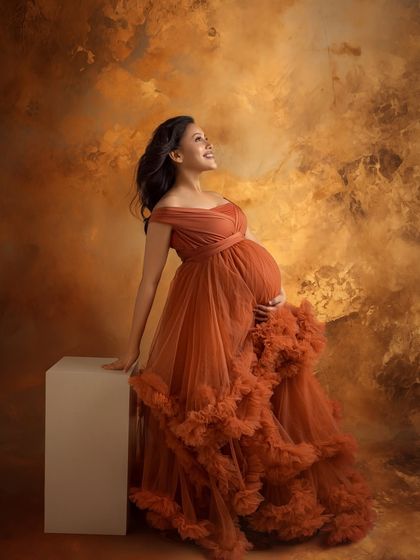 A joyful and radiant portrait in a stunning, rust-colored ruffled gown, looking up with hope and happiness.