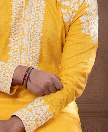 A detail shot of the sleeve cuff on the zesty yellow kurta, showing the intricate floral embroidery.