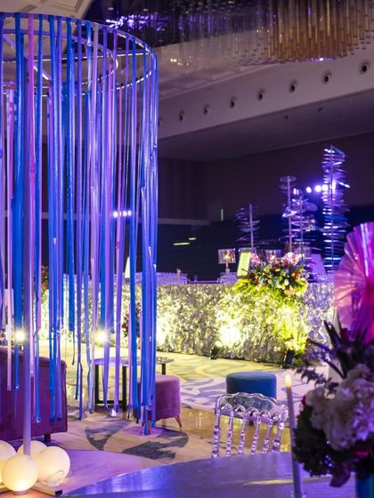 A lounge area featuring a unique light installation made of blue and purple ribbons. This creative decor element provides soft, ambient lighting and serves as a modern art piece within the event space.