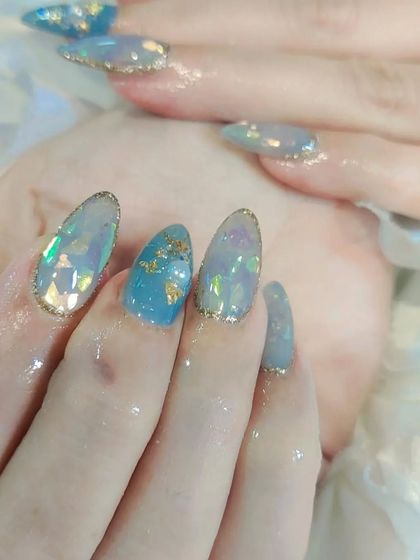 A close-up of a mesmerizing design with a translucent blue base, encapsulated iridescent flakes, and delicate gold foil accents.