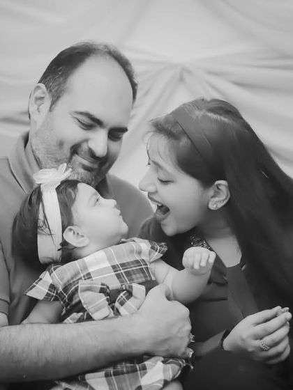 A black and white version of the sweet interaction between a father, sister, and new baby, highlighting the emotional connection.