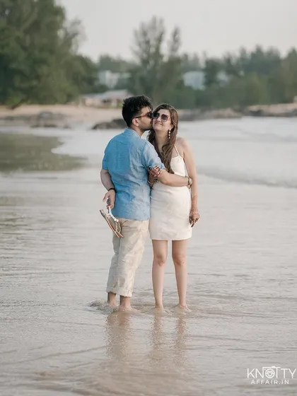 A sweet kiss on the cheek while standing in the gentle waves. This candid moment captures the relaxed and happy vibe of their Thailand beach photoshoot.
