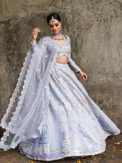 We adore pastel shades for modern wedding functions. This full-length view shows a gorgeous lavender lehenga with intricate silver mirror work and a beautifully detailed border on the dupatta, offering a soft yet glamorous look for an engagement or sangeet.