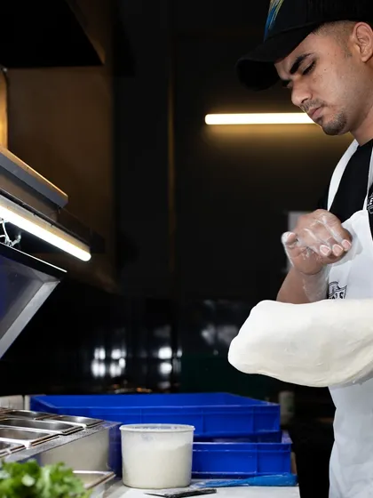 It all starts with the dough. Our pizzaiolo carefully stretches the base, a skill that takes practice and passion to perfect, ensuring a thin center and a puffy cornicione.