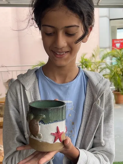 A proud moment for this 12-year-old artist, holding her finished sea-themed mug. After 15 days of learning, it's wonderful to see her so happy with her creation.
