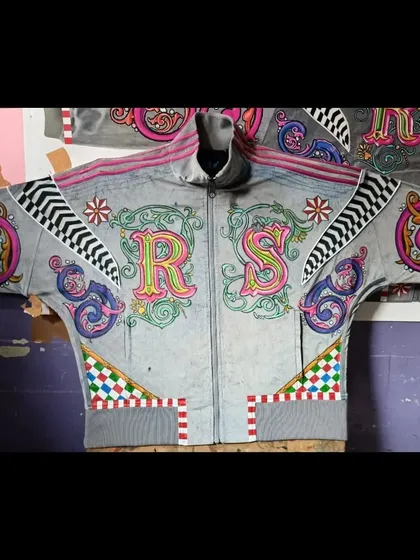 A full, flat-lay view of the completed 'RS' initialed hoodie. This perspective showcases the entire composition, from the central letters to the decorative elements on the shoulders and waistband.