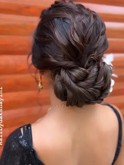 This is a modern, textured updo, perfect for a sangeet or reception. I wove together different sections to create this intricate, romantic bun, finishing it with a delicate floral accessory for a touch of elegance.