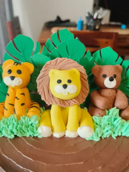 A detailed shot of the handmade fondant tiger, lion, and bear toppers that bring this jungle cake to life.