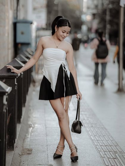 A stylish portrait on a city bridge, with the blurred background suggesting a bustling urban environment. The composition is clean and focused on the model.