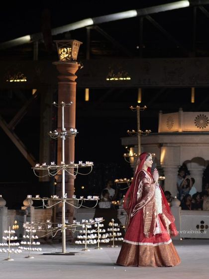 Kriti Sanon on the ramp, surrounded by diyas, at the 'Dharohar Kashi ki' fashion show. The setting adds a layer of cultural richness to the fashion event.