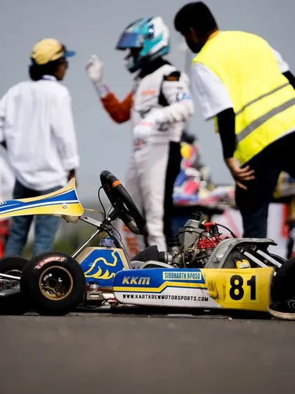 A kart sits on the grid, with a mechanic and driver discussing strategy.
