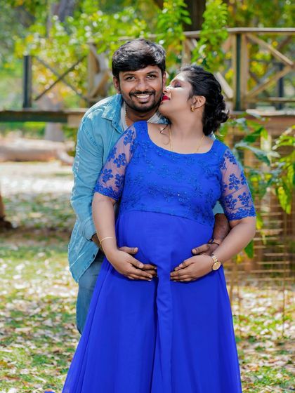 A sweet and playful moment between a couple in a park. The partner's kiss on the cheek and their hands on the baby bump create a photo full of love and happiness.