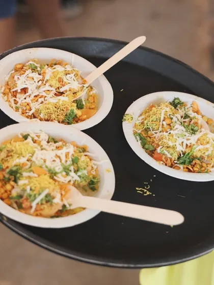 Our chaat is always a crowd-pleaser. This is a close-up of our savory chaat bowls, topped with fresh coriander, sev, and cheese, ready to be served. It's the perfect light and flavorful snack for house parties and events.