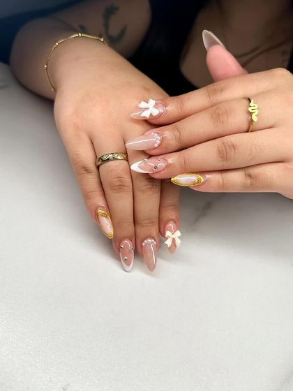 Another view of this intricate design, showing the combination of 3D bows, gold accents, and white French tips.