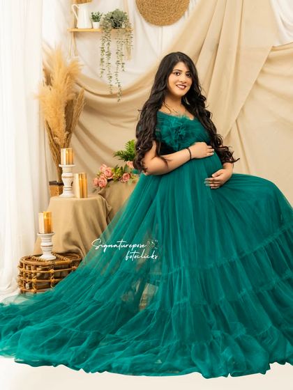 A beautiful seated portrait in a flowing emerald green gown, set against a cozy, candle-lit boho backdrop.