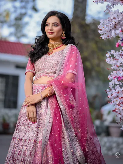 The bride posing against a wall of cherry blossoms, her elegance complementing the delicate floral decor.