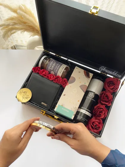 This image shows the personalized Rakhi bracelet being added to the luxury trunk hamper for a brother, completing the perfect gift.
