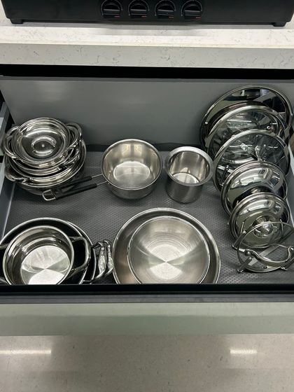 A deep drawer under the stove, perfectly organized with steel pots and pans. Keeping cookware close to the cooking area is key for an efficient kitchen workflow.