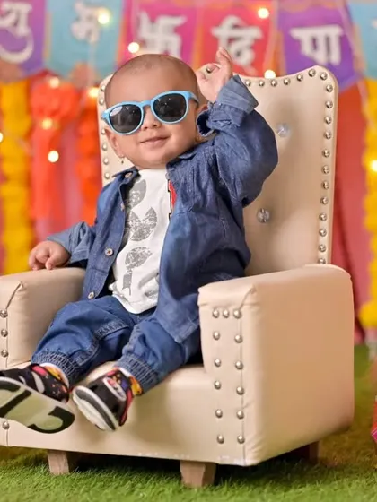 A cool and modern Diwali celebration in the studio. This little boy in a denim jacket and sunglasses brings all the style, sitting on a miniature throne in a brightly lit, festive setting.