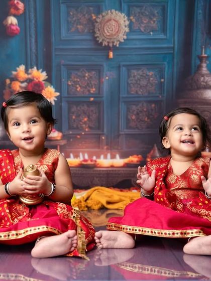 Double the trouble, double the fun. These twin girls in their matching red traditional outfits are radiating joy in this festive, candle-lit setting.