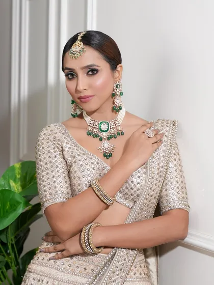 A confident and poised bridal look. The subtle smokey eye adds a touch of modern glam to her traditional ivory and green ensemble.