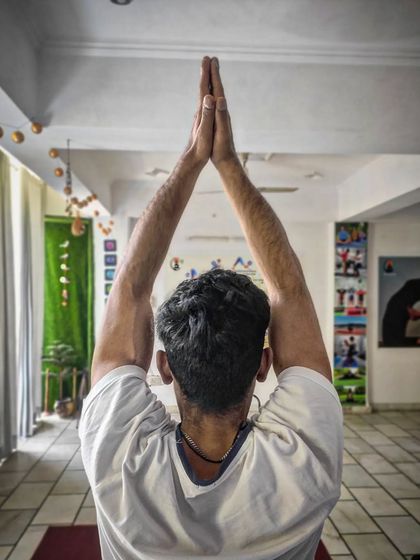 A student raises his hands in prayer at the start of a class. We begin each session by centering ourselves, setting an intention, and honoring the traditional yogic lifestyle.