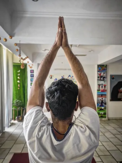 A student raises his hands in prayer at the start of a class. We begin each session by centering ourselves, setting an intention, and honoring the traditional yogic lifestyle.