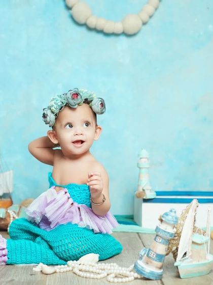 Our little mermaid strikes a pose. The floral crown and seashell props complete this enchanting underwater look.