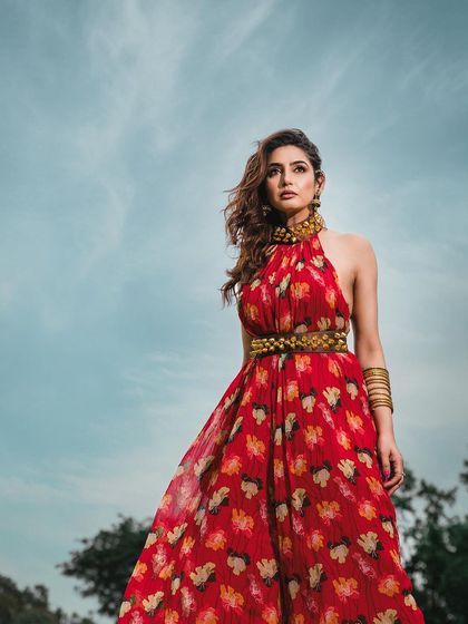 A low-angle shot against a bright blue sky, making the model in her vibrant red dress appear powerful and statuesque. This technique is great for creating heroic and memorable fashion images.