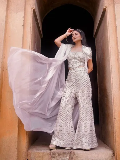 A dynamic shot capturing the movement of a flowing white cape on an Indo-Western outfit. The model is positioned in an archway, which frames her beautifully and adds architectural interest to this fashion photograph.