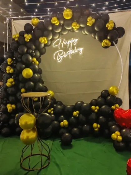 Another view of the black and gold birthday balloon arch, showing how it looks with the surrounding fairy lights. This setup is great for creating a focused party corner on a terrace or in a garden.