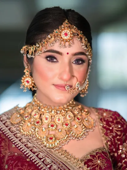 A close-up showcasing the harmony between the makeup and the magnificent jewellery. The soft purple undertones in the eyeshadow pick up the hues in her maroon lehenga, creating a cohesive, regal look.