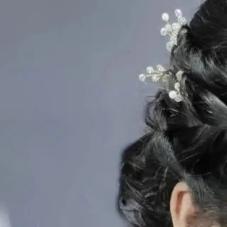 A detailed shot of a bridal updo. You will learn to create structured yet soft hairstyles that hold throughout a long event, using pins and accessories for a flawless finish.