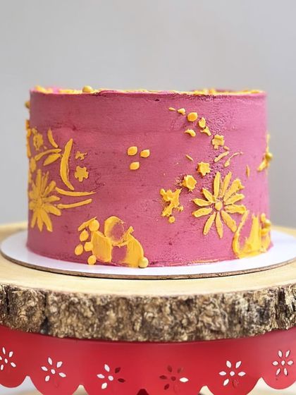 A side view of the custom-designed pink and yellow cake, highlighting the delicate, hand-piped floral pattern.
