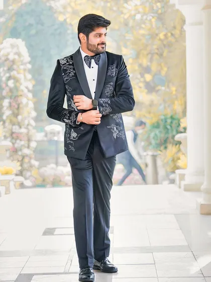 A full-length shot of the groom looking dapper in his modern, embroidered tuxedo. The outdoor colonnade provides a classic and sophisticated backdrop.