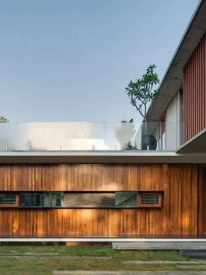 A detailed look at the facade's material palette. The warmth of the vertical timber cladding contrasts with the smooth, cool surface of the white walls and the transparency of the glass railing, creating a rich textural composition.