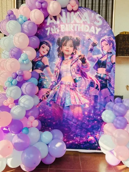 A vertical shot of the 'Huntrix' themed backdrop, showing the full sweep of the pastel balloon garland.