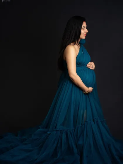 A classic maternity silhouette. This side-profile pose is perfect for showcasing the beautiful curve of the baby bump against the dark, dramatic background.
