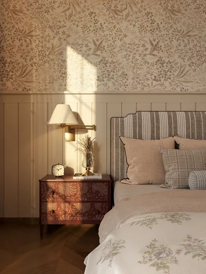A close-up of the bedside, where a classic lamp sits atop a vintage-style nightstand. The striped headboard and floral wallpaper create a graceful, age-old feel.