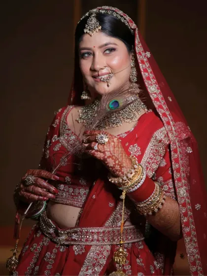 Holding a peacock feather, this bride channels divine elegance. Her makeup is dreamy and radiant, designed to match her royal red lehenga and timeless vibe.