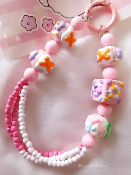 Another angle of the pink and white beaded charm, showing the texture and detail of the handmade candy-like beads.