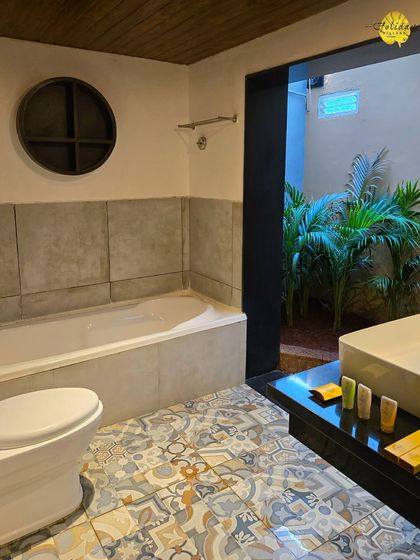 The bathroom in one of our suites, featuring a full bathtub and an entrance to a private open-air section. The unique tile work adds a touch of artistic flair to the space.