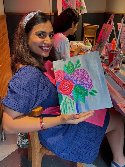 A smiling participant holding her beautiful floral abstract painting. The joy of creating something with your own hands is unmatched.