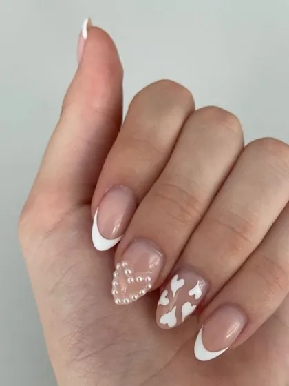 A super cute and romantic French manicure. This set includes classic white tips, a pearl heart accent nail, and a nail with tiny white hearts.