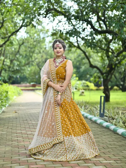 A bold and beautiful mustard yellow lehenga. This piece stands out with its unique color and detailed embroidery, paired with a contrasting pink and gold jewellery set for a complete festive look.