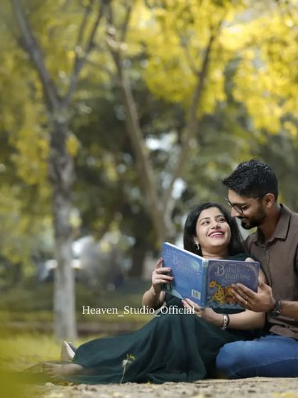 Sharing a story with their little one already. This charming outdoor shot of the couple reading a book together under a tree is both whimsical and deeply meaningful.