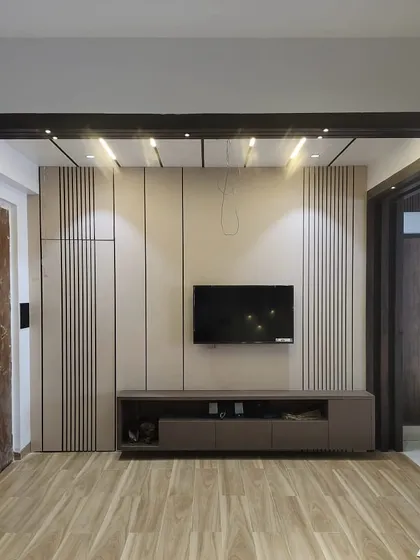 A work-in-progress shot of a living room. This shows the installation of the TV unit with vertical fluted panels and wooden flooring, giving clients a peek into the construction phase.
