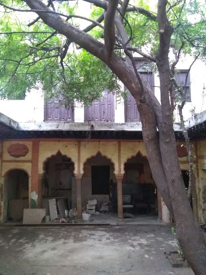 The courtyard in its dilapidated state, with the central tree already suggesting its future role as the focal point of the revived space.