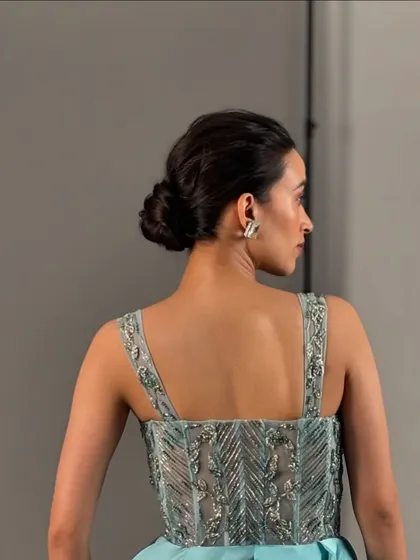 A back view of the classic low bun hairstyle. This showcases the clean and secure styling required for long commercial shoots, ensuring the look holds up from every angle.
