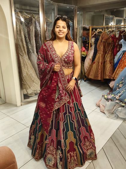 A happy client trying on a vibrant multi-color lehenga. The mix of patterns and colors makes it a perfect choice for a lively Mehendi or Sangeet event.
